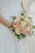 A joyful bride holding a beautifully arranged wedding bouquet from Maskaya.