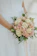 Close-up of a vibrant bridal bouquet with soft pink roses and greenery, tied with a silk ribbon.