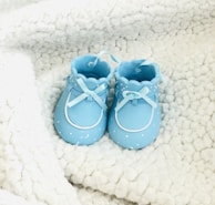 Close-up of a pair of tiny baby shoes resting on a cozy knitted blanket.