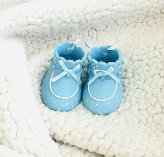 Close-up of tiny baby shoes in mint pastel color on a cream blanket