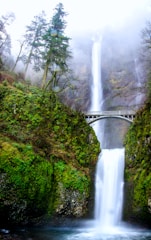 white bridge over waterfalls during daytime