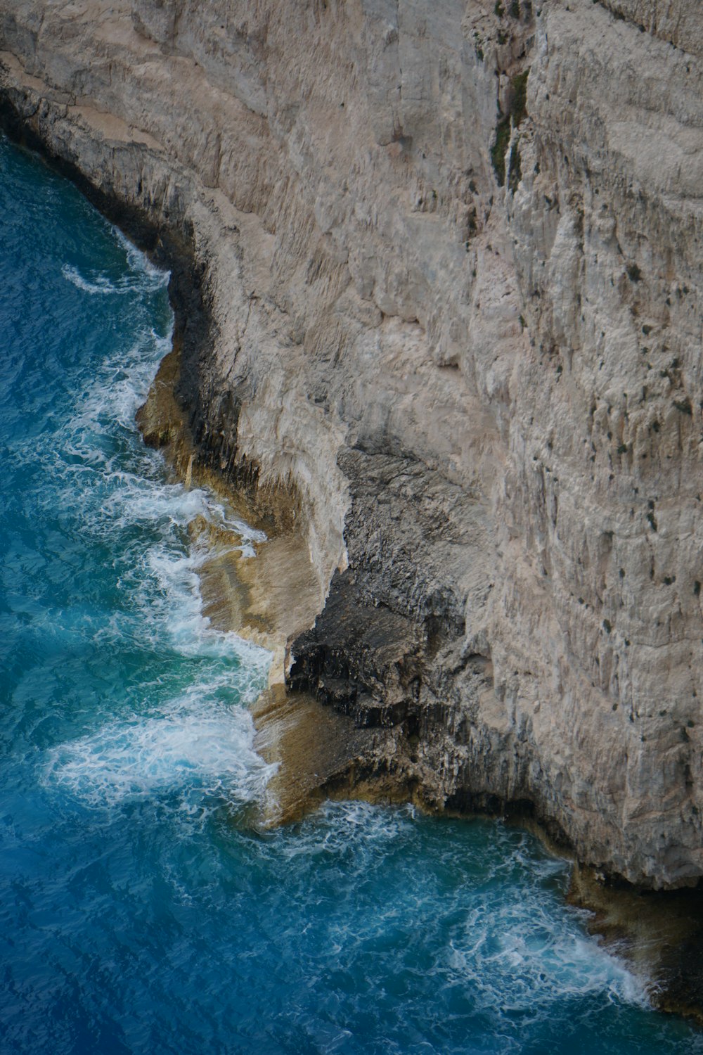 brown rocky mountain beside blue sea during daytime