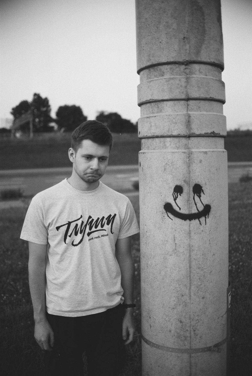 boy in white crew neck t-shirt standing beside concrete post