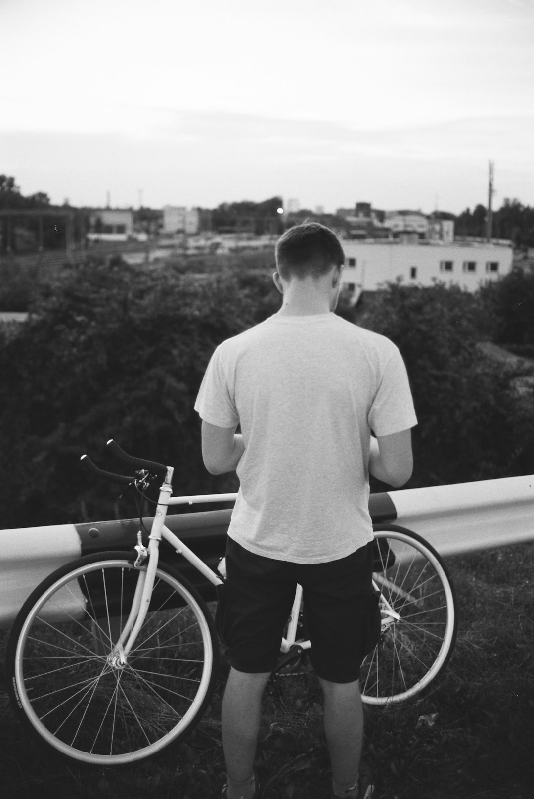 man in white crew neck t-shirt and black shorts standing beside bicycle during daytime