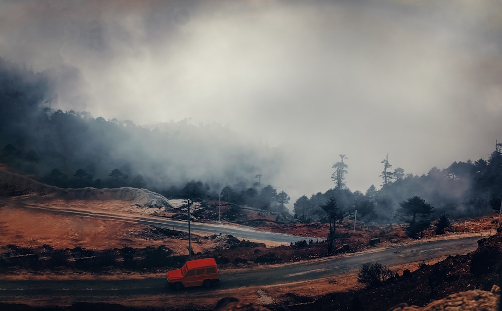 red and black bus on road near trees and mountain during daytime