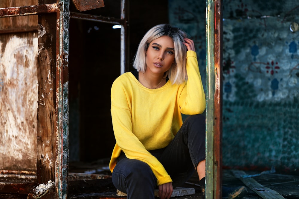 woman in yellow long sleeve shirt and black pants sitting on brown wooden chair