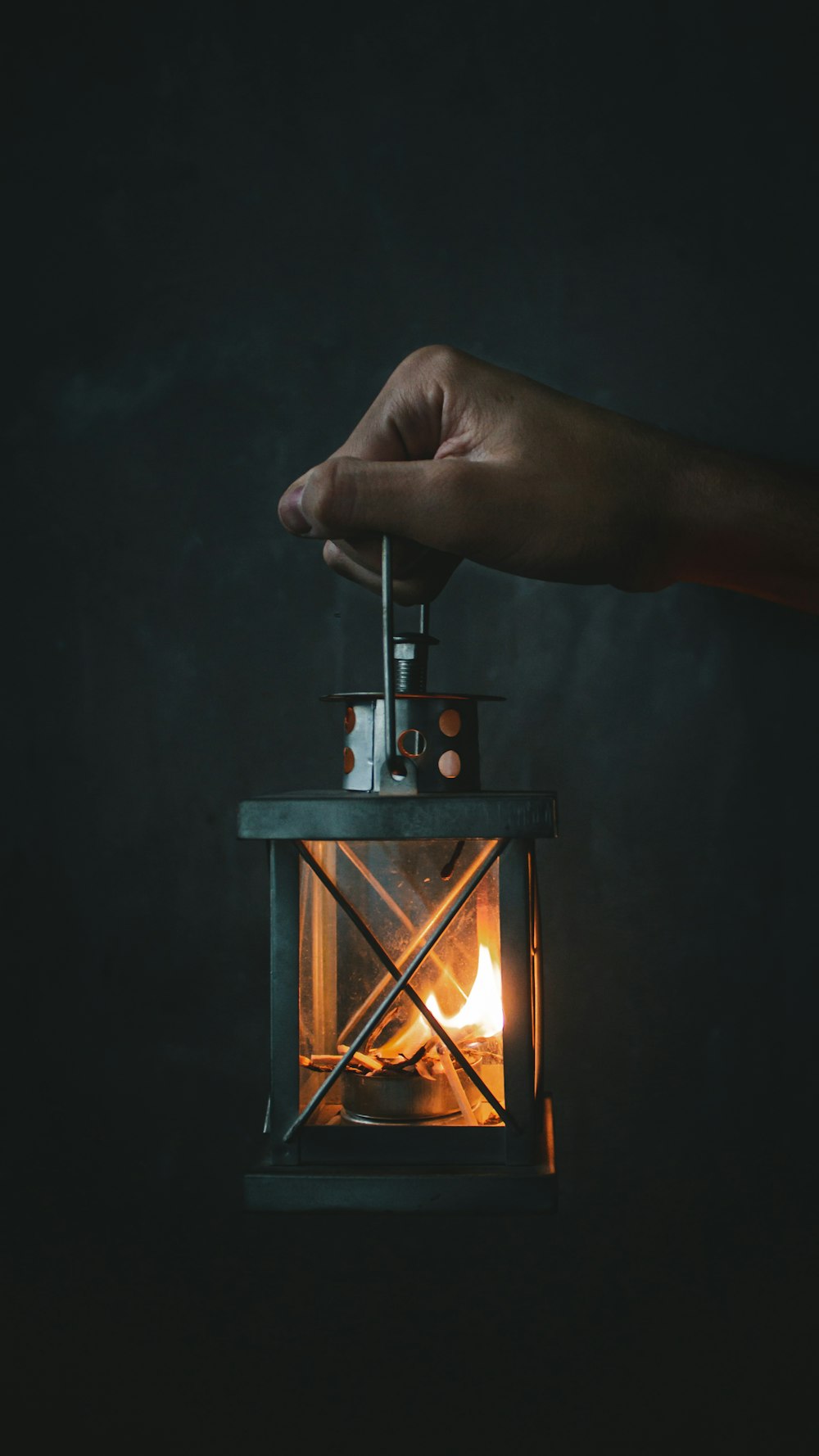 person holding lighted candle on brown wooden candle holder