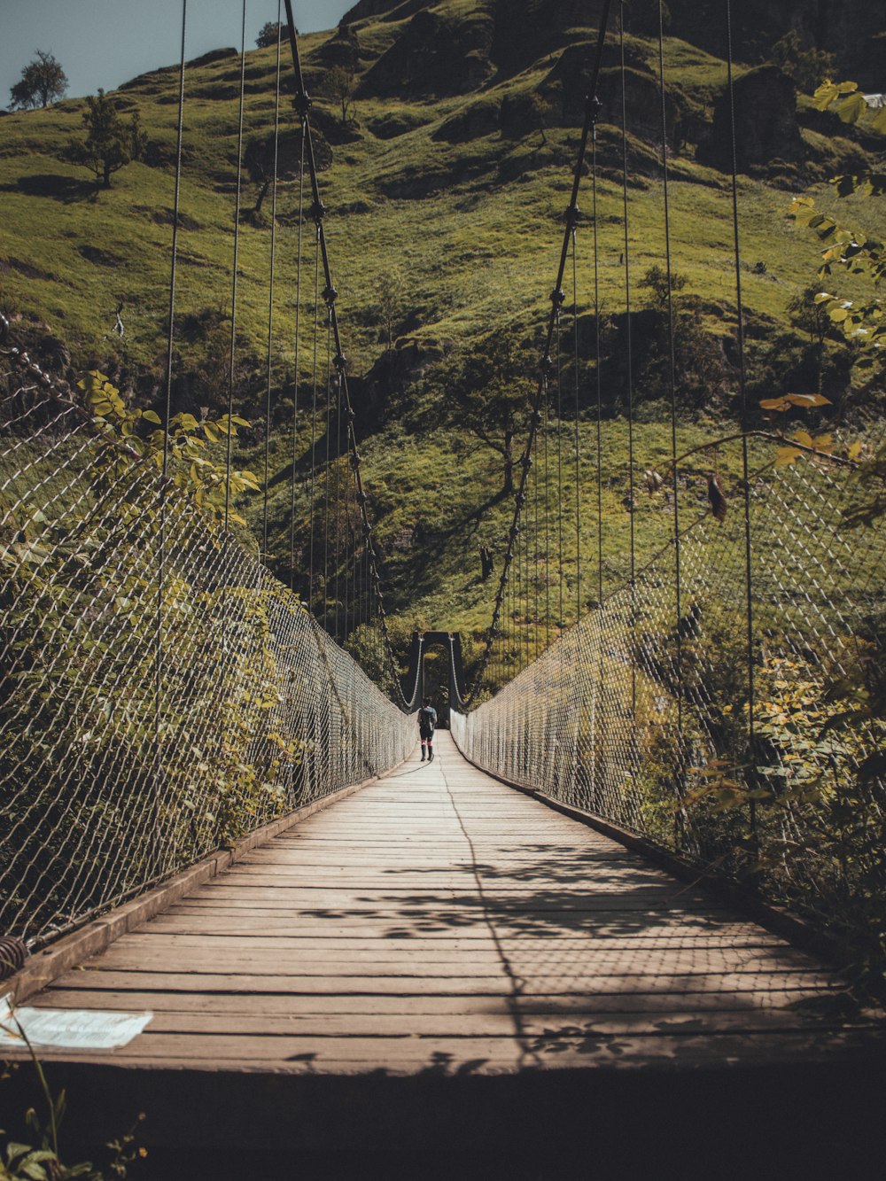 brown wooden bridge over green mountains during daytime