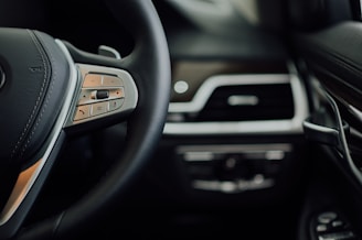 Close-up of a luxury car's steering wheel inside a sleek, modern vehicle.