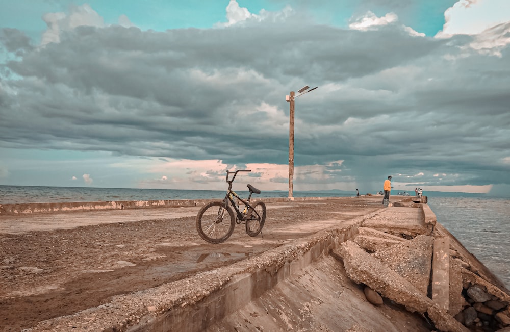 black bicycle on brown sand near body of water during daytime