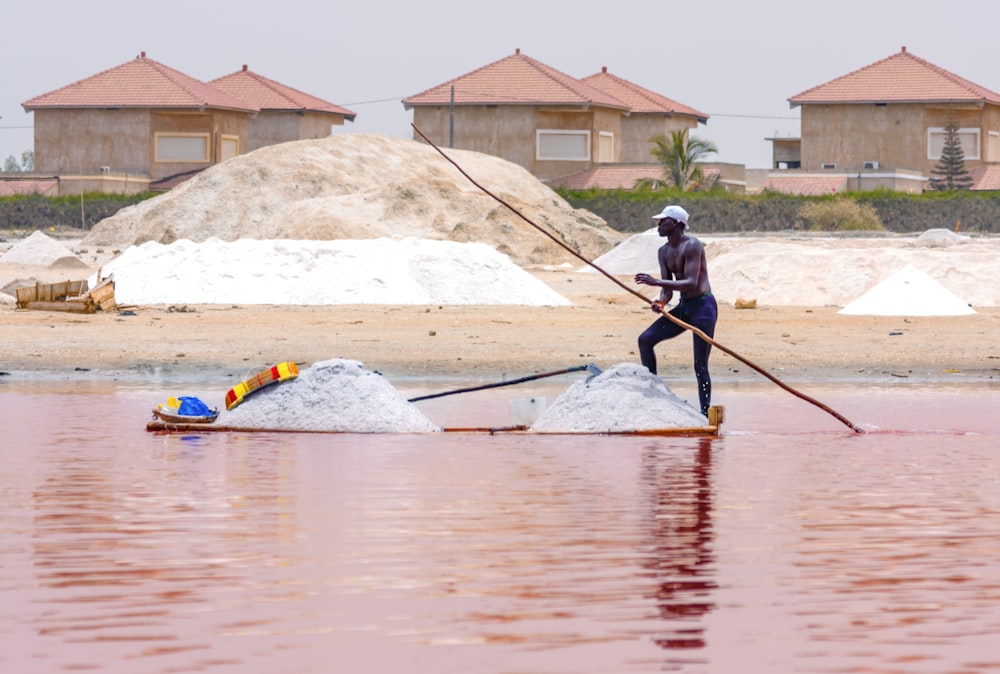 hombre en chaqueta negra y pantalones azules montando en kayak azul en el cuerpo de agua durante