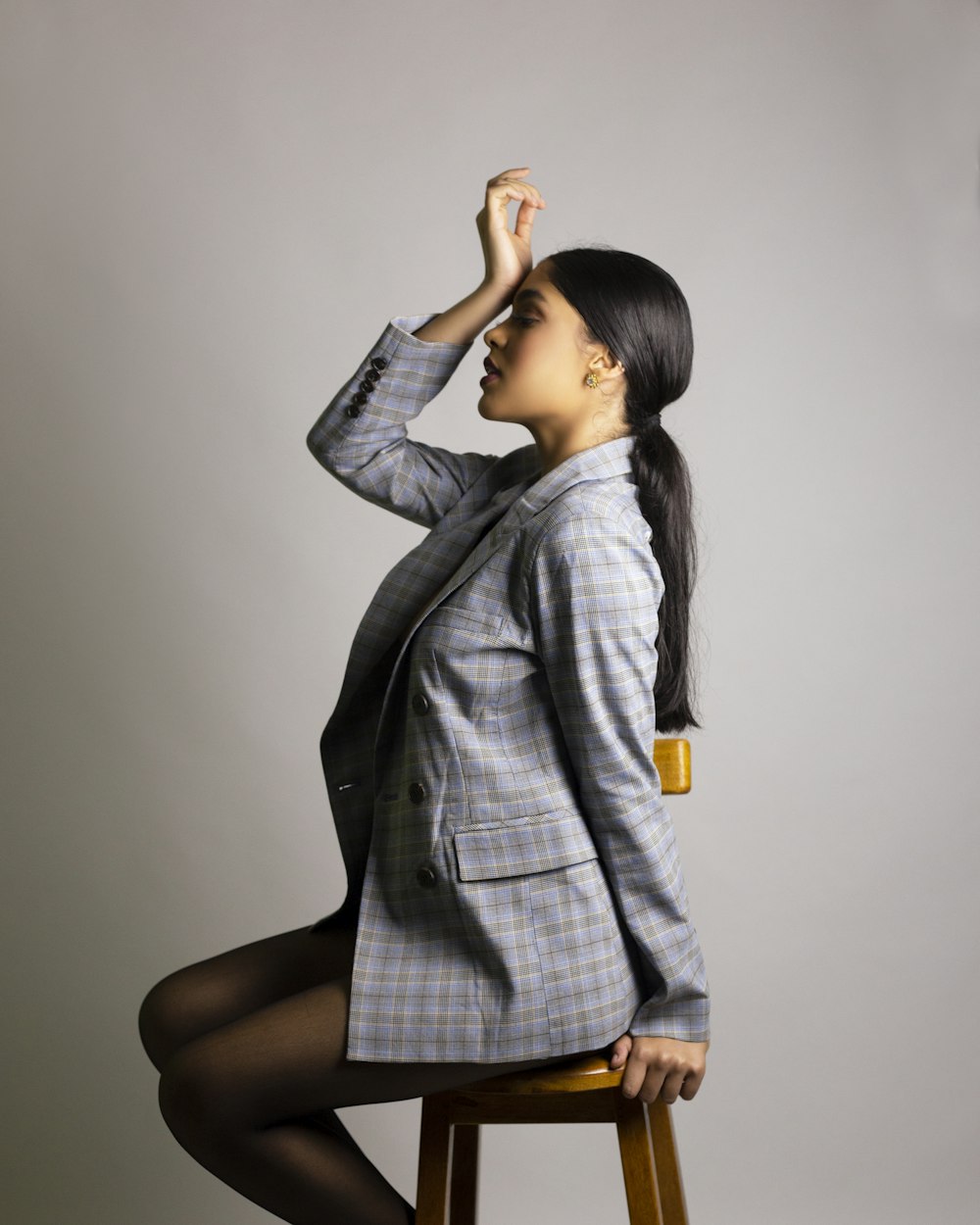 woman in gray and white plaid coat sitting on black chair