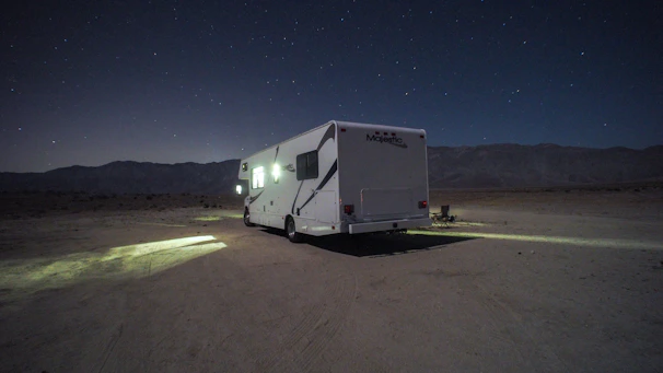 A rugged male van dweller setting up camp beside his van in a golden hour desert landscape.