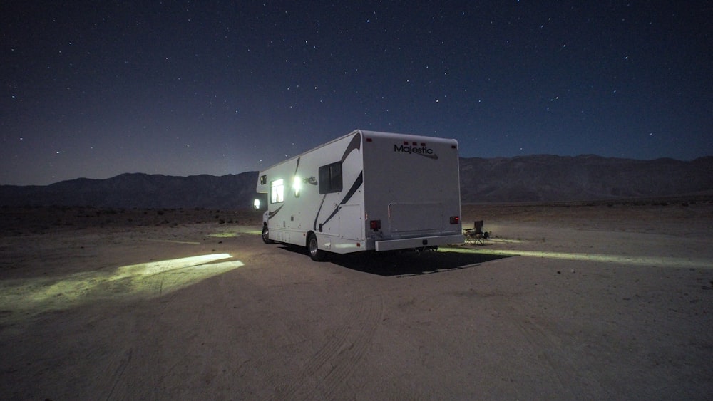 white and gray rv trailer on brown sand during night time