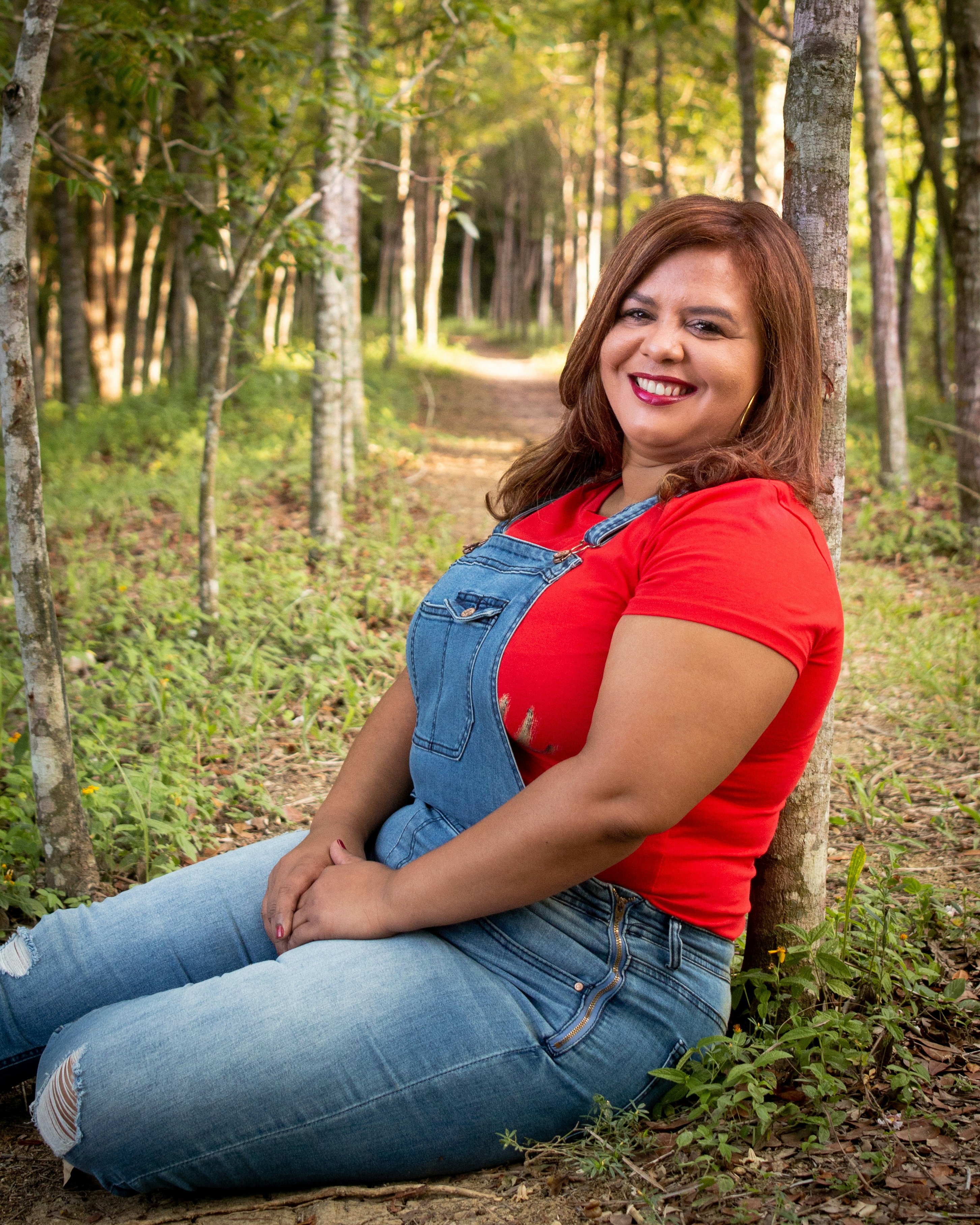Donna in t-shirt rossa e jeans blu in denim che si siede a terra