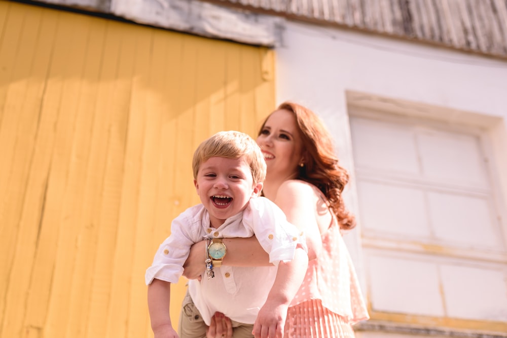 woman in blue and white plaid dress shirt carrying girl in white shirt