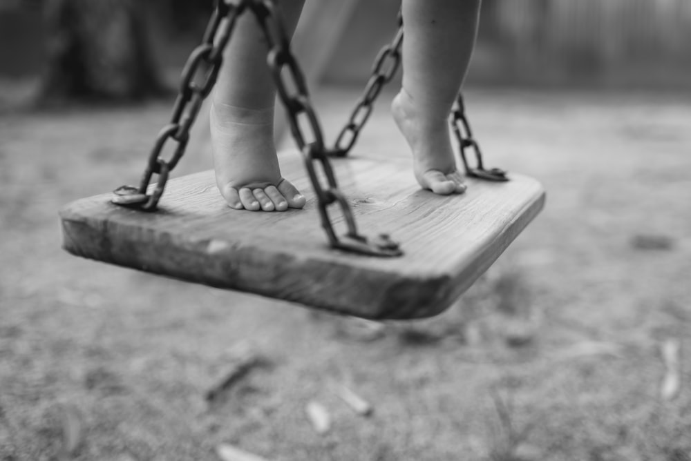 grayscale photo of person sitting on swing