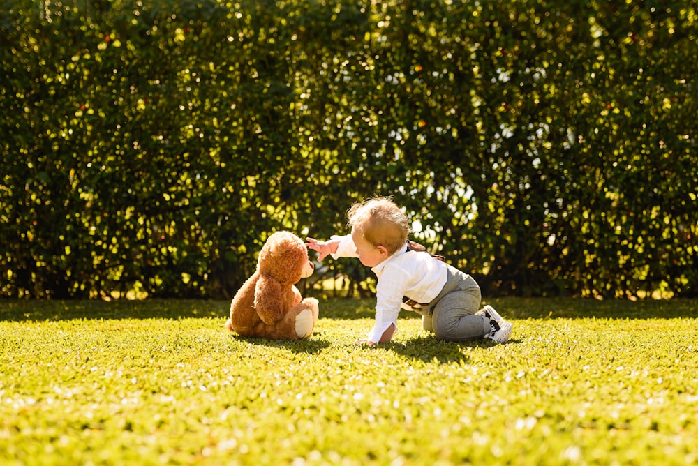 child in white long sleeve shirt and gray pants sitting on yellow flower field during daytime