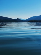 body of water near mountain during daytime