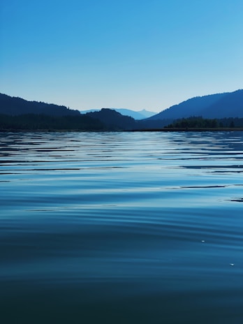 body of water near mountain during daytime