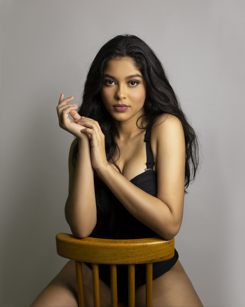 woman in black tank top sitting on brown wooden chair