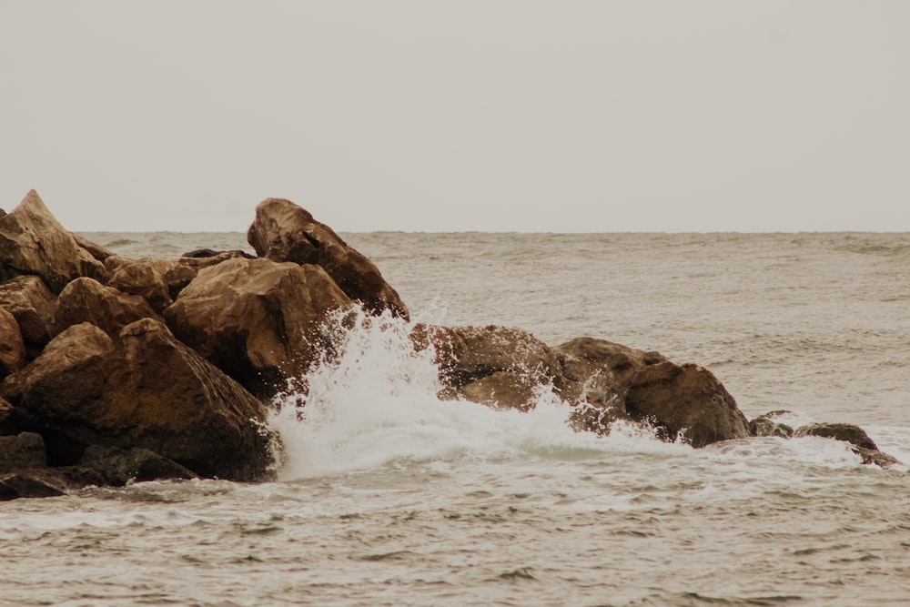 formação rochosa marrom na água do mar durante o dia