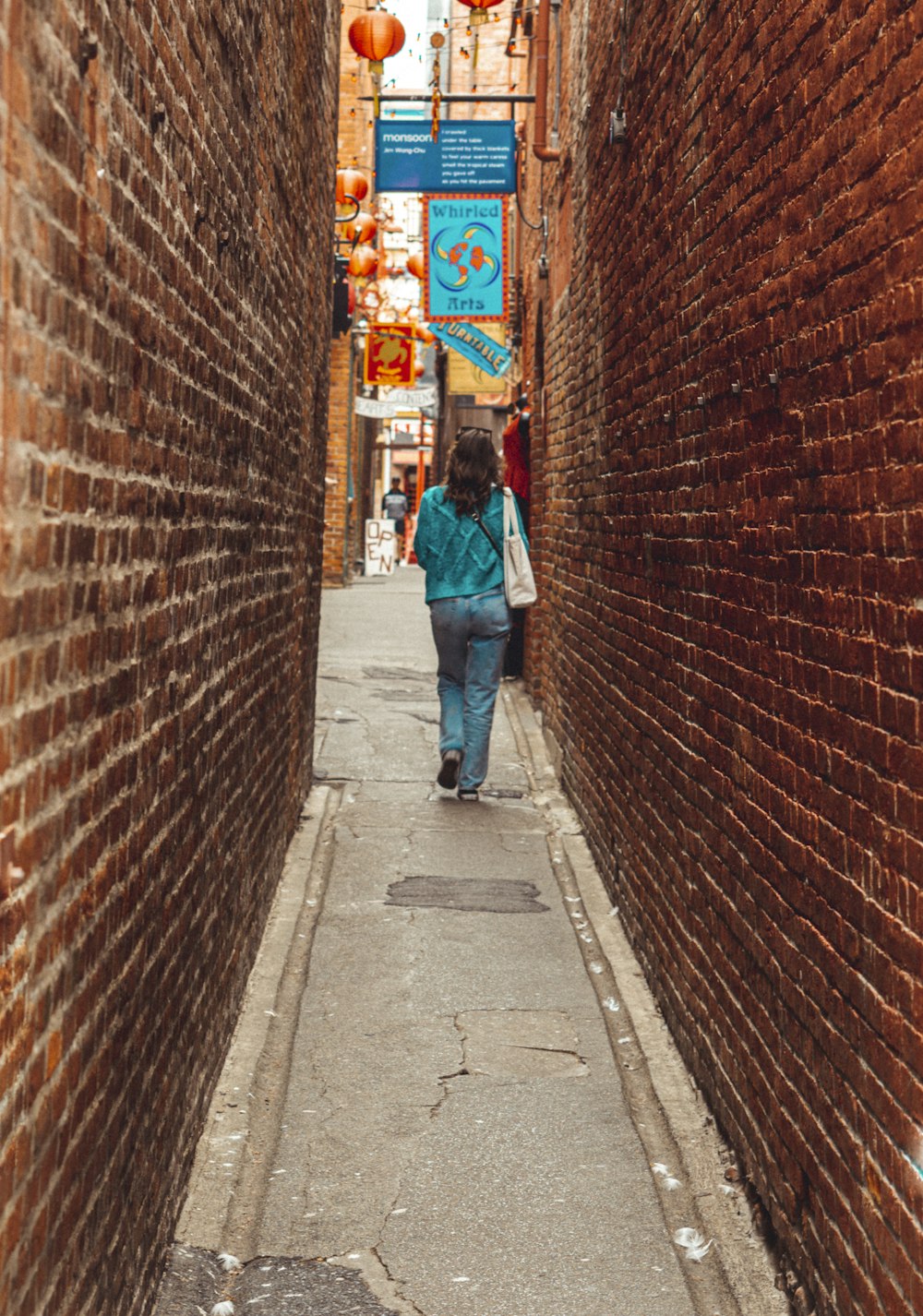 Mujer en jeans de mezclilla azul caminando en la acera durante el día