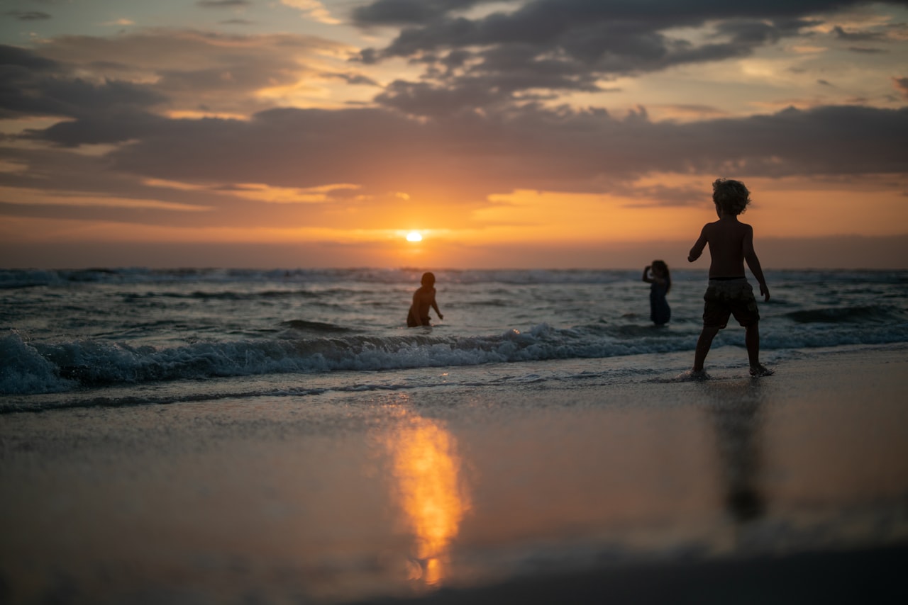Kids playing in waves during sunset