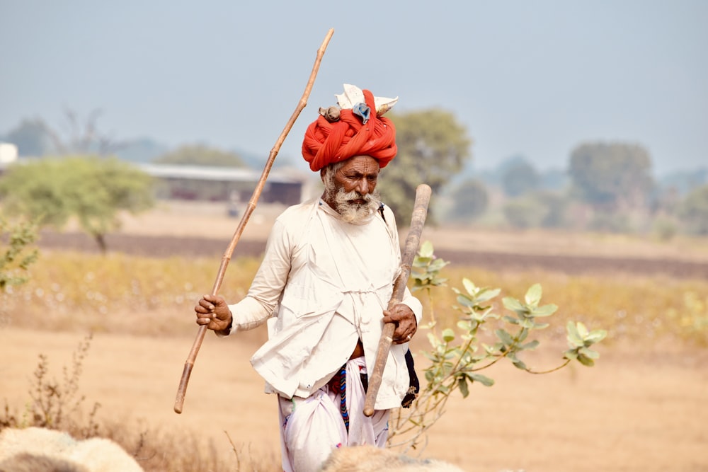 woman in white long sleeve shirt and white pants holding brown stick during daytime