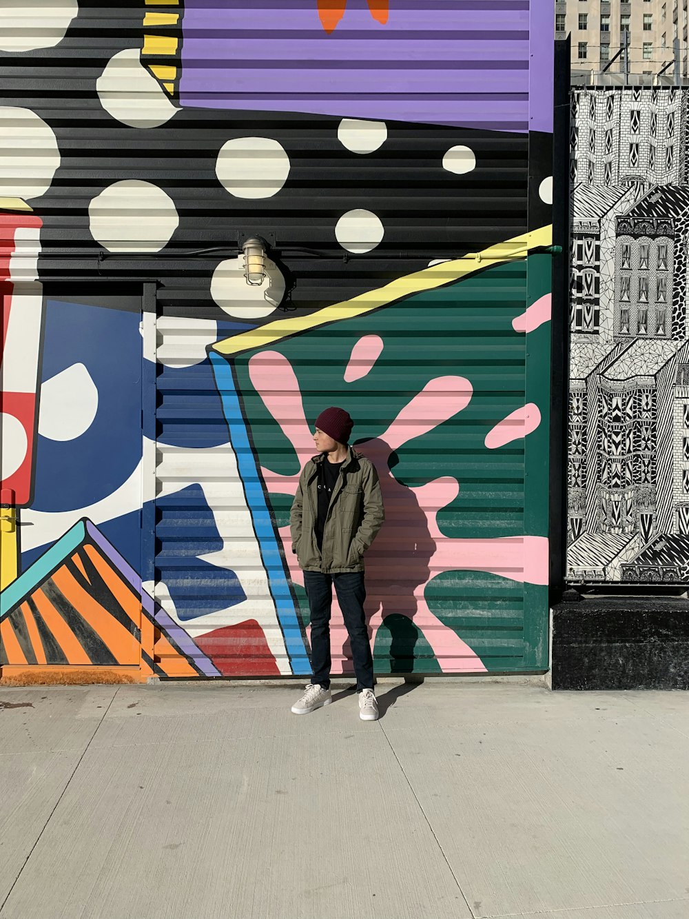 woman in brown coat standing beside wall with graffiti