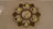 A decorative wall clock with a flower-like pattern, featuring multiple digital time displays and a central analog display showing a date. The frame has intricate designs with leaf shapes surrounding the displays, presenting a blend of modern digital and traditional decorative elements.