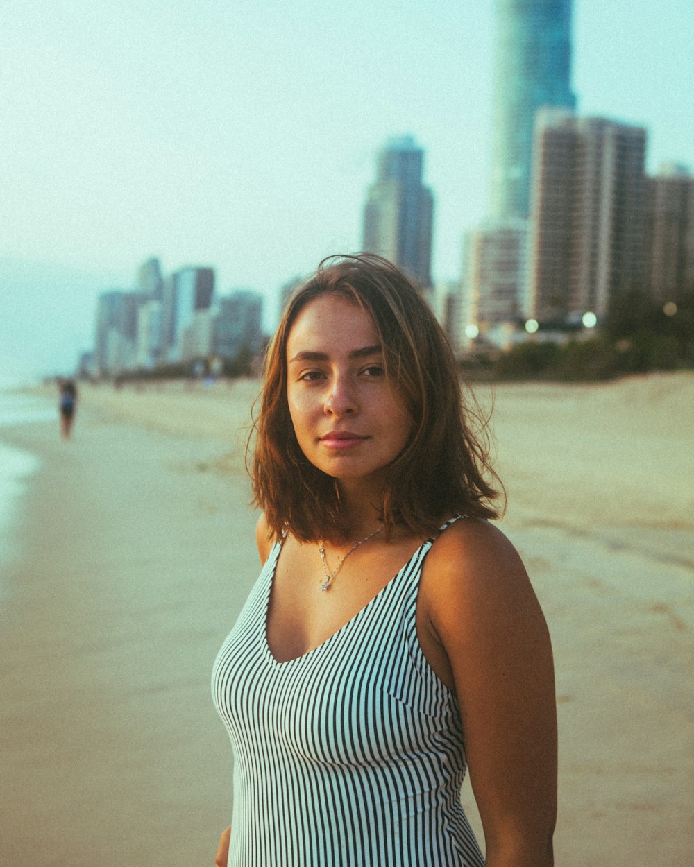 woman in white and black stripe tank top standing on beach during daytime