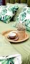 Close-up of a plush king-size bed with crisp white linens and emerald green accent pillows.