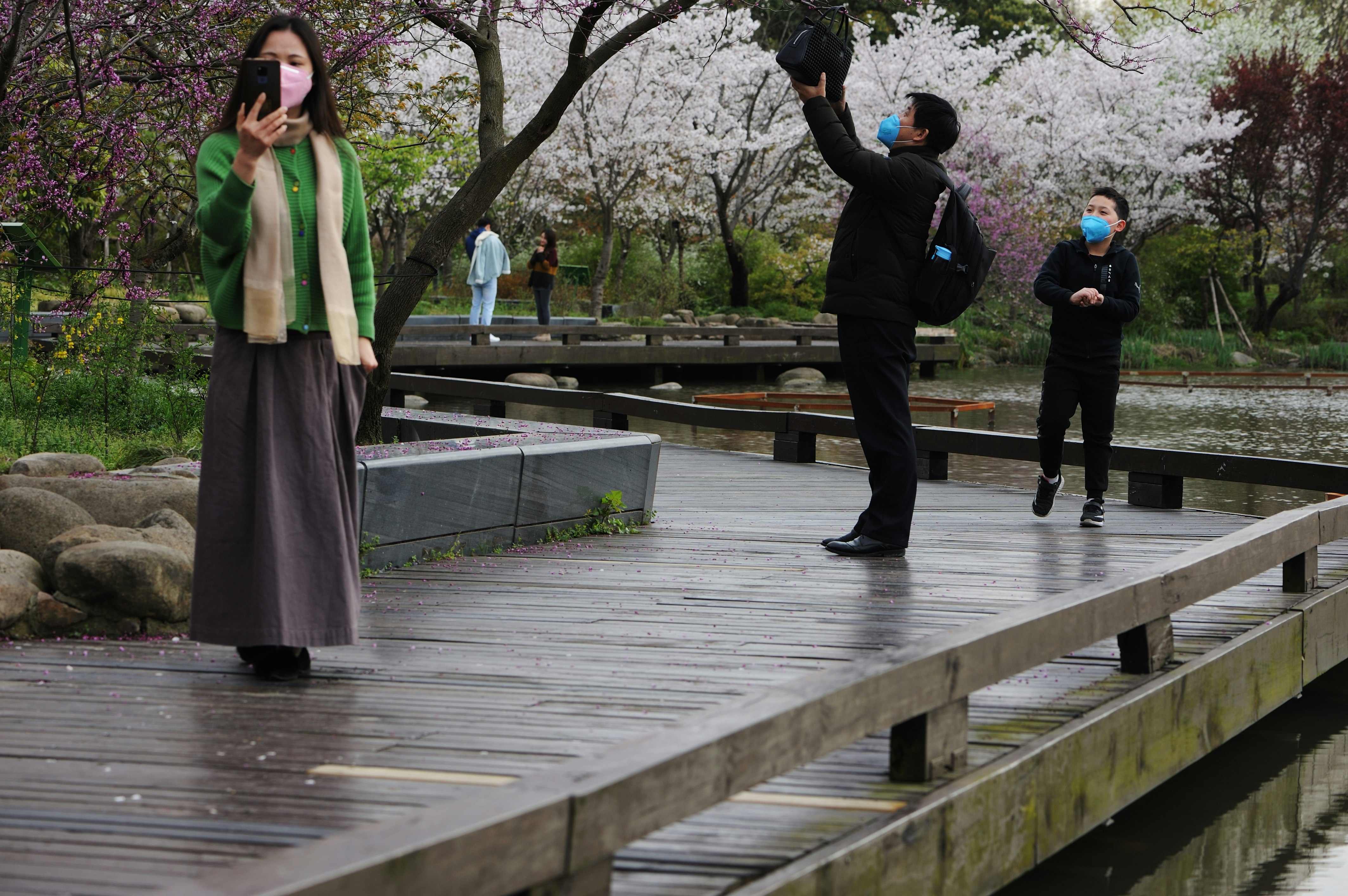 woman in green long sleeve shirt and black pants holding black dslr camera