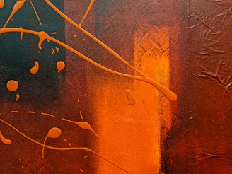 A textured abstract painting featuring rich reds and oranges applied with scrapers and sponges creating dynamic movement