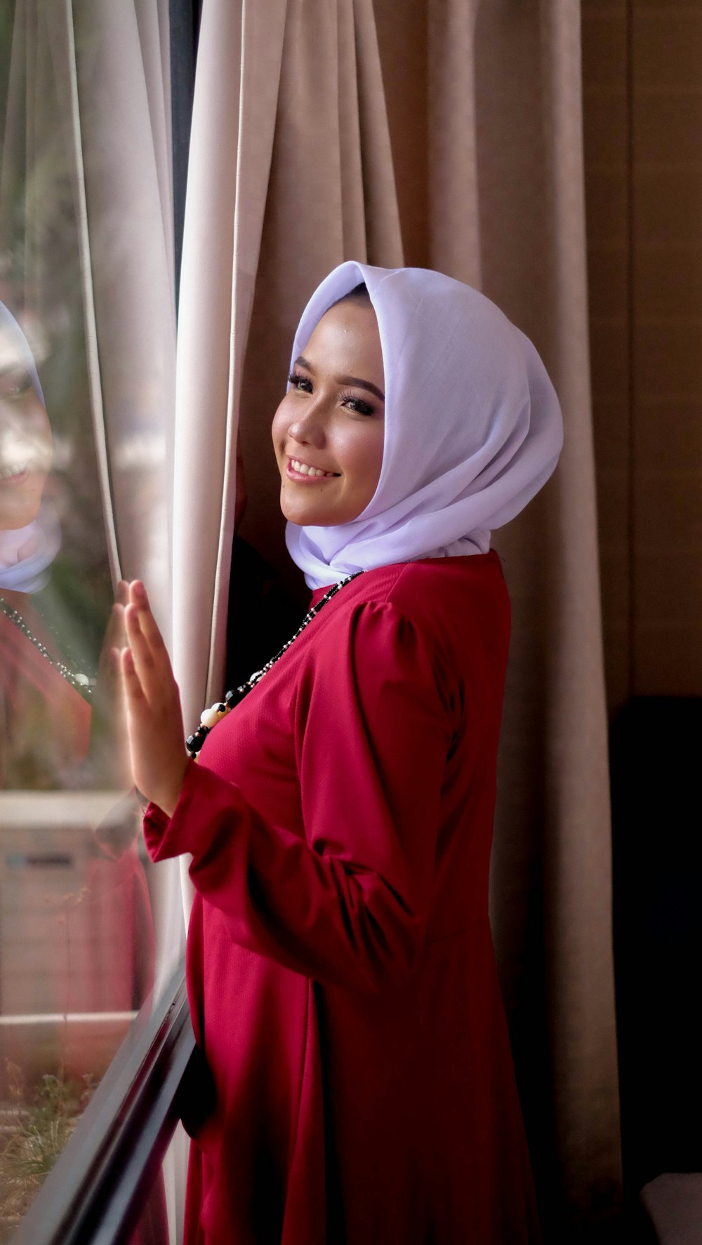 woman in red hijab holding glass window