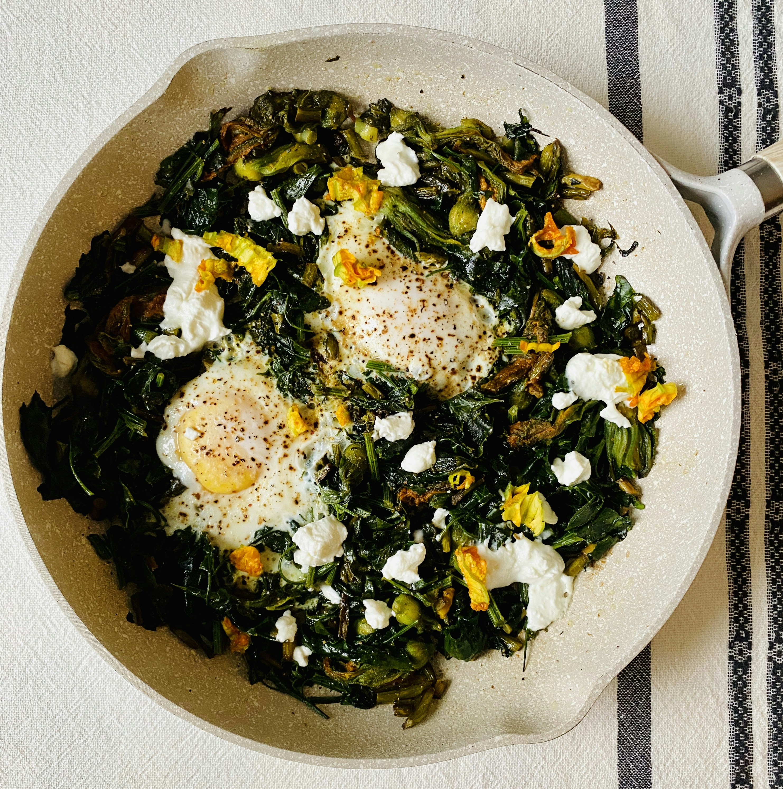 Sautéed kale with eggs and cheese in a ceramic skillet