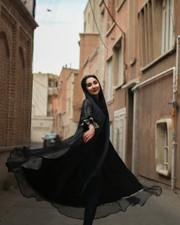 A candid shot of a woman twirling in a flowing dress on a cobblestone street.