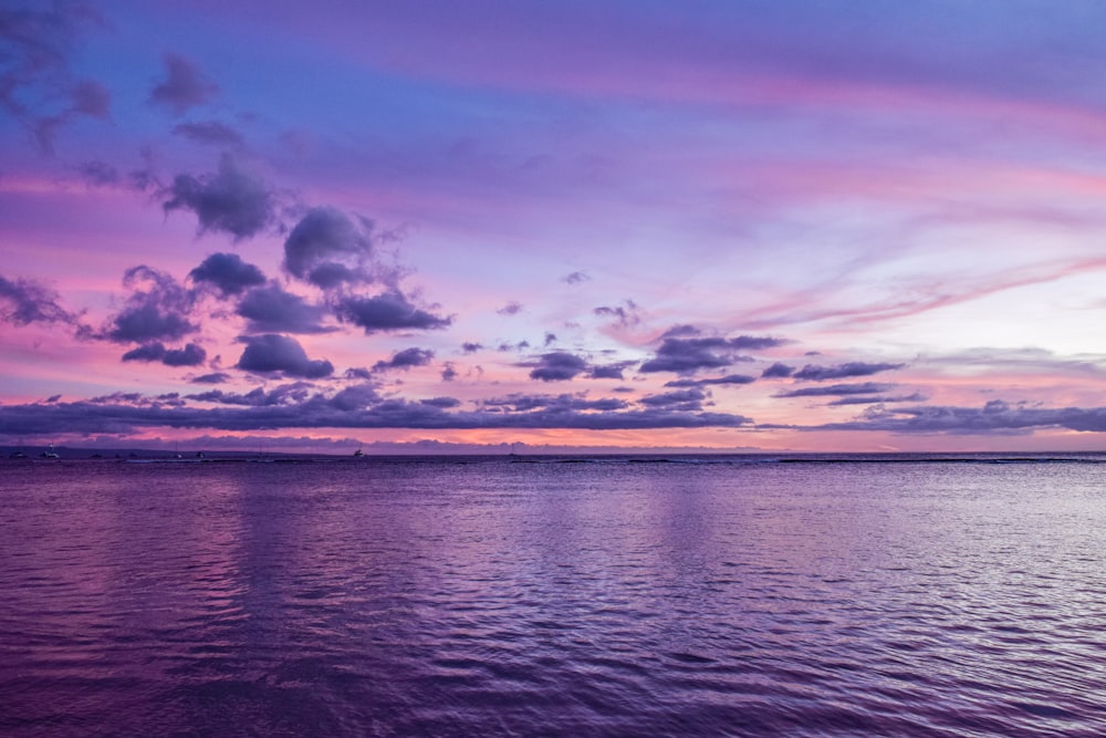 um pôr do sol roxo e azul sobre um corpo de água