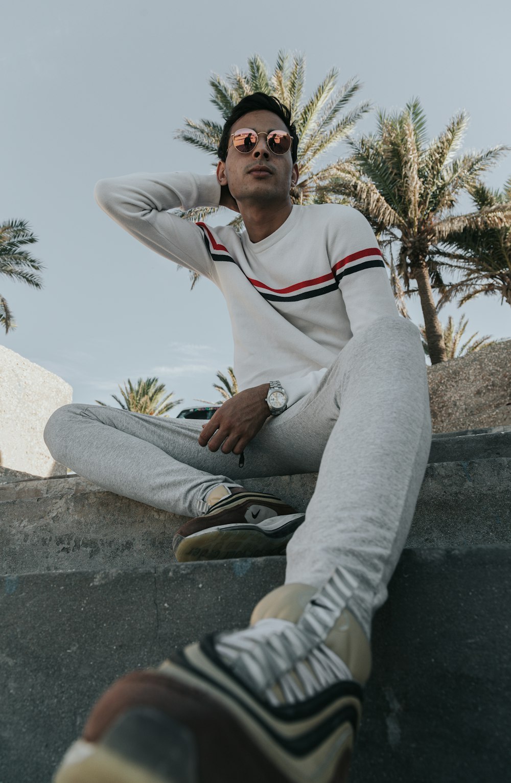 man in white and red long sleeve shirt and gray pants sitting on gray concrete bench