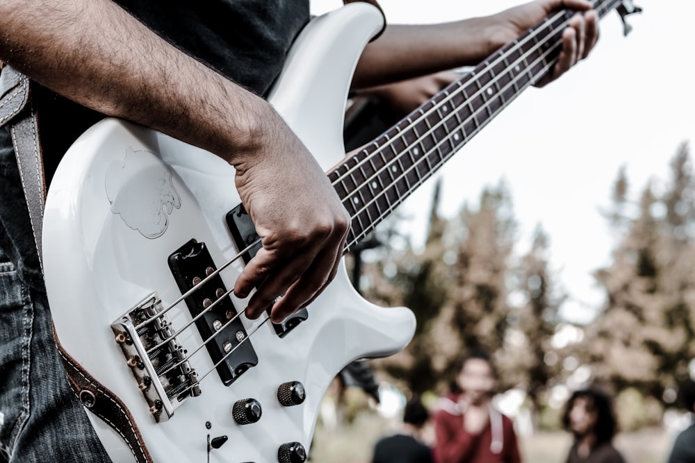 man in black t-shirt playing white electric guitar