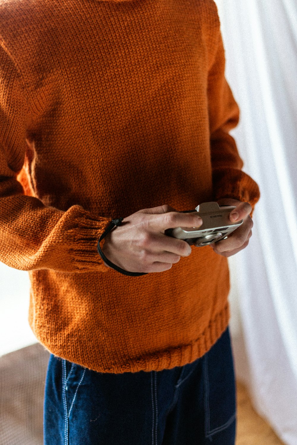 person in brown sweater holding silver smartphone