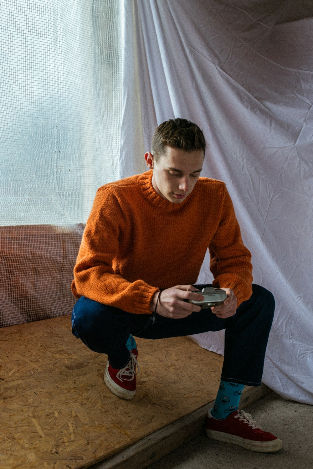 boy in orange sweater and blue pants sitting on brown couch