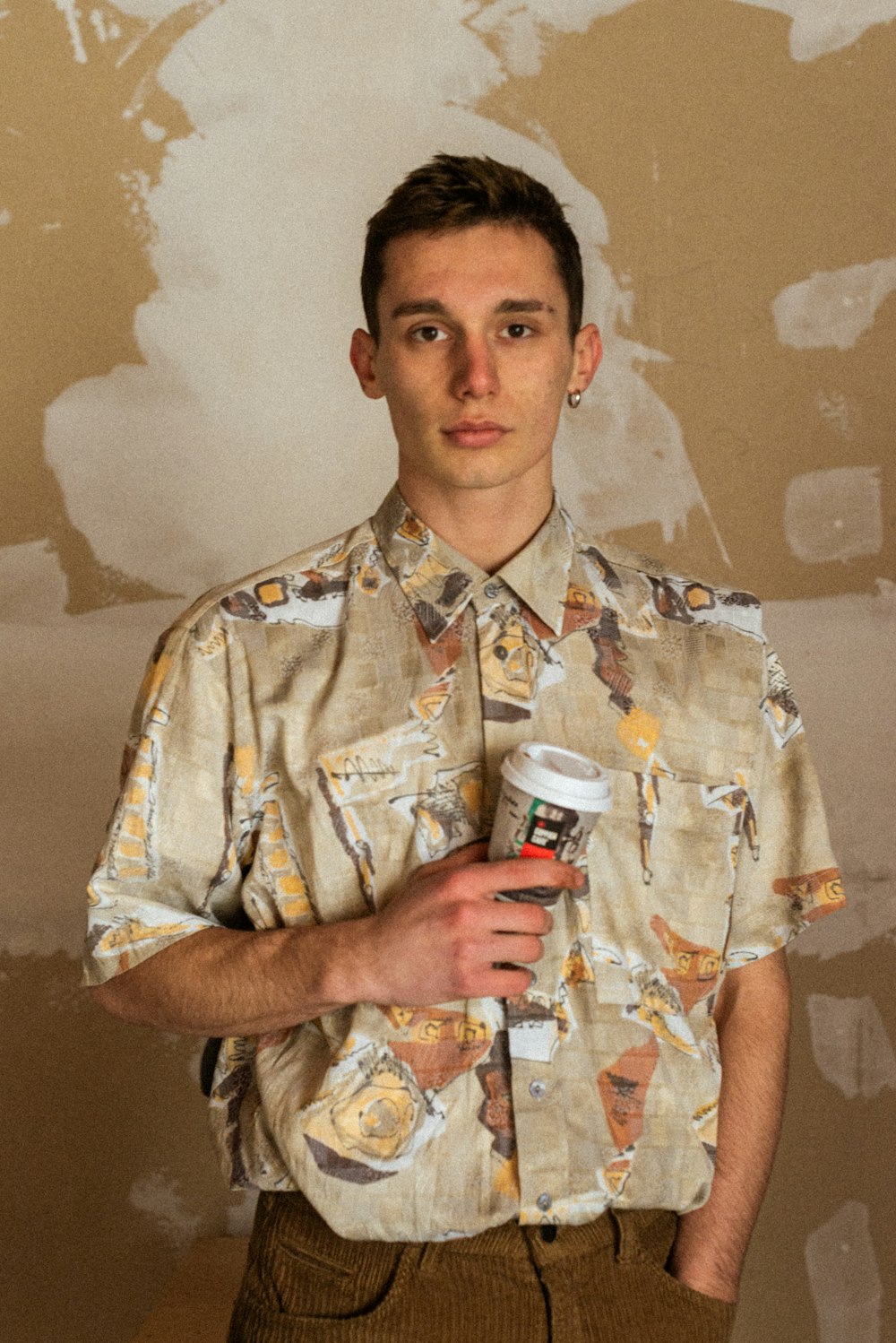 man in yellow and white floral button up shirt holding white and red ceramic mug