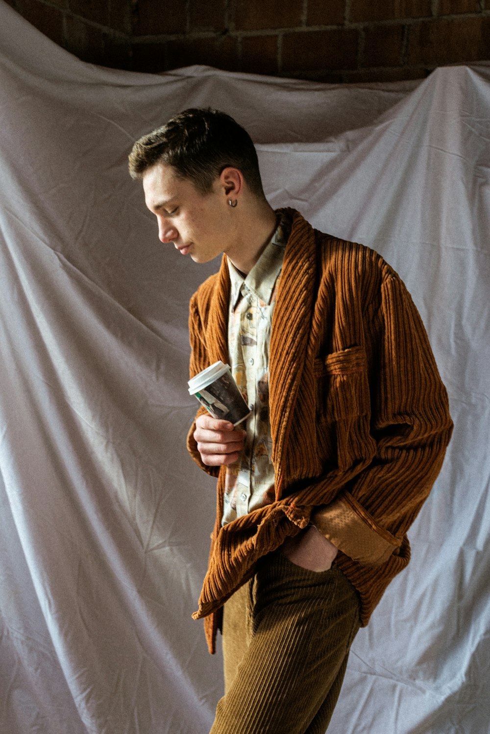 man in brown and beige coat holding black ceramic mug