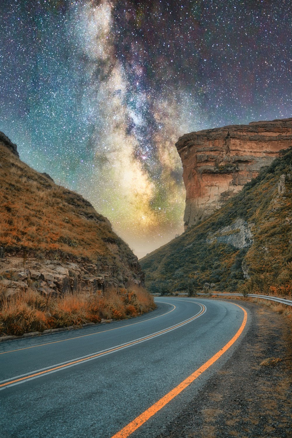 gray asphalt road between brown rock formation during daytime