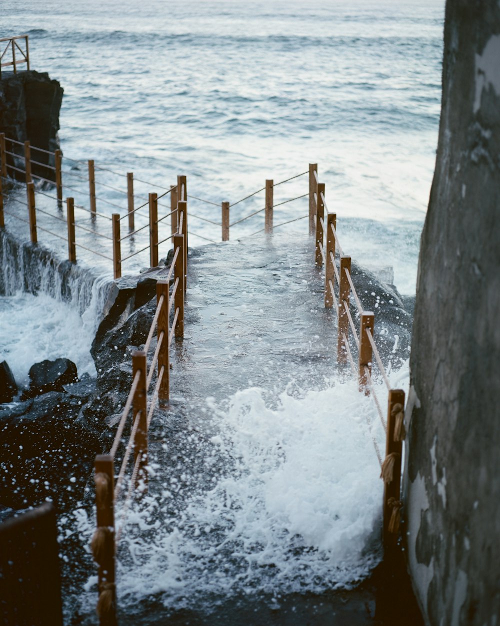 brown wooden fence on sea shore during daytime