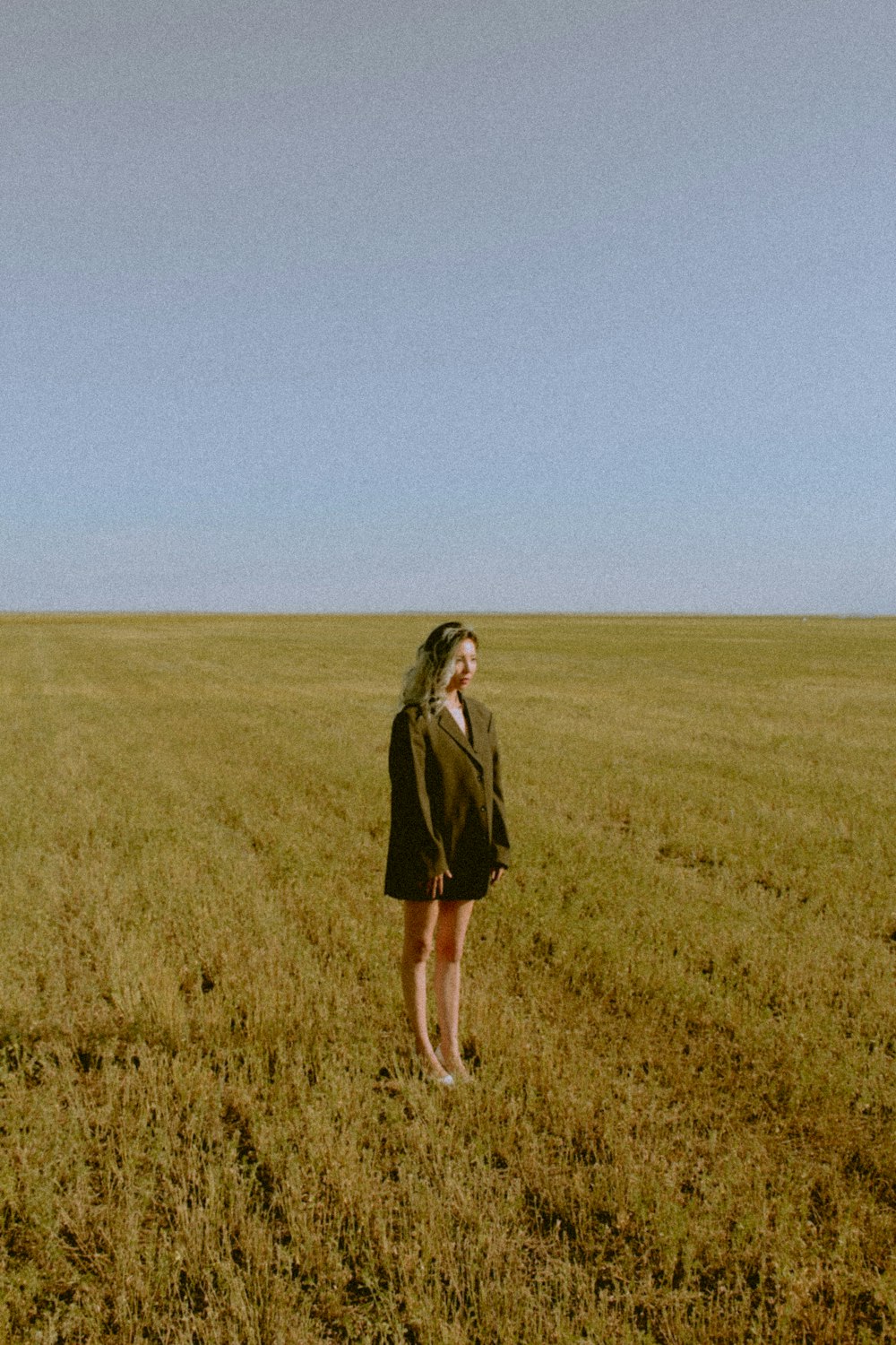 woman in black coat standing on green grass field during daytime