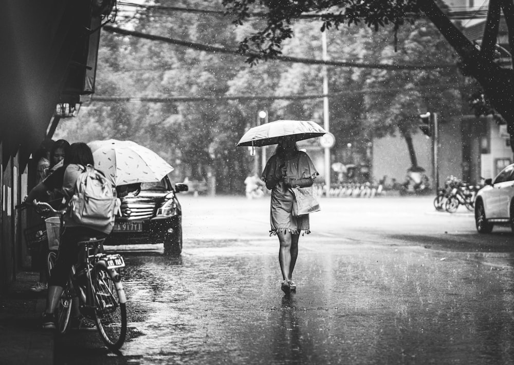 grayscale photo of man and woman walking on street