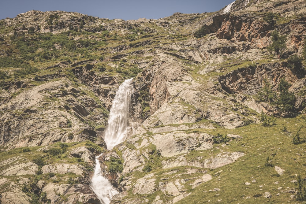 waterfalls on green grass covered hill during daytime